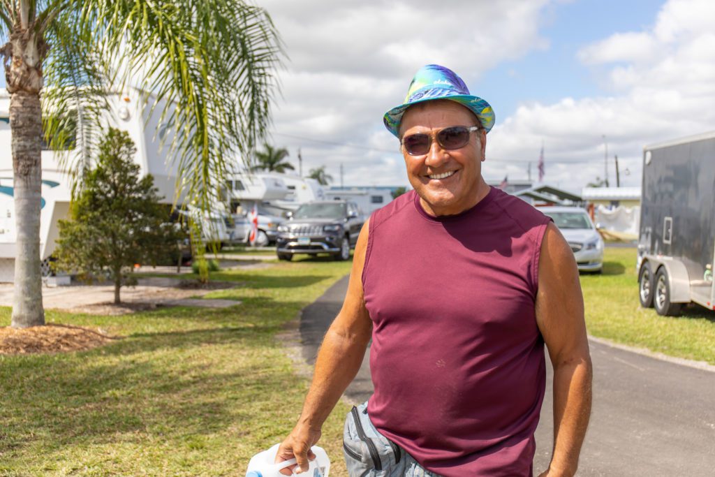 A man wearing his red sleeveless shirt and a colorful bucket hat